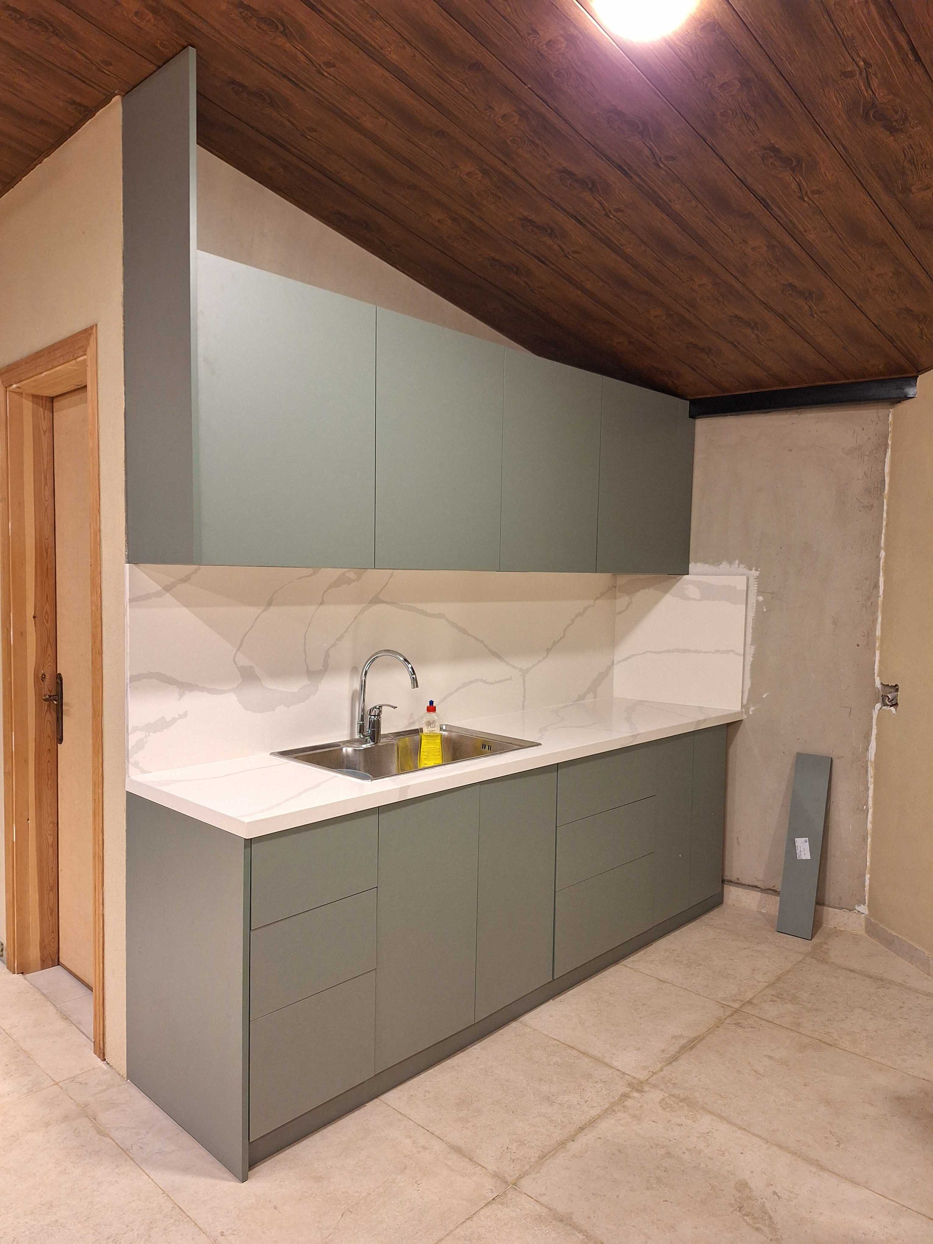 Laurel Green kitchen viewed from the side beneath a sloped wood ceiling