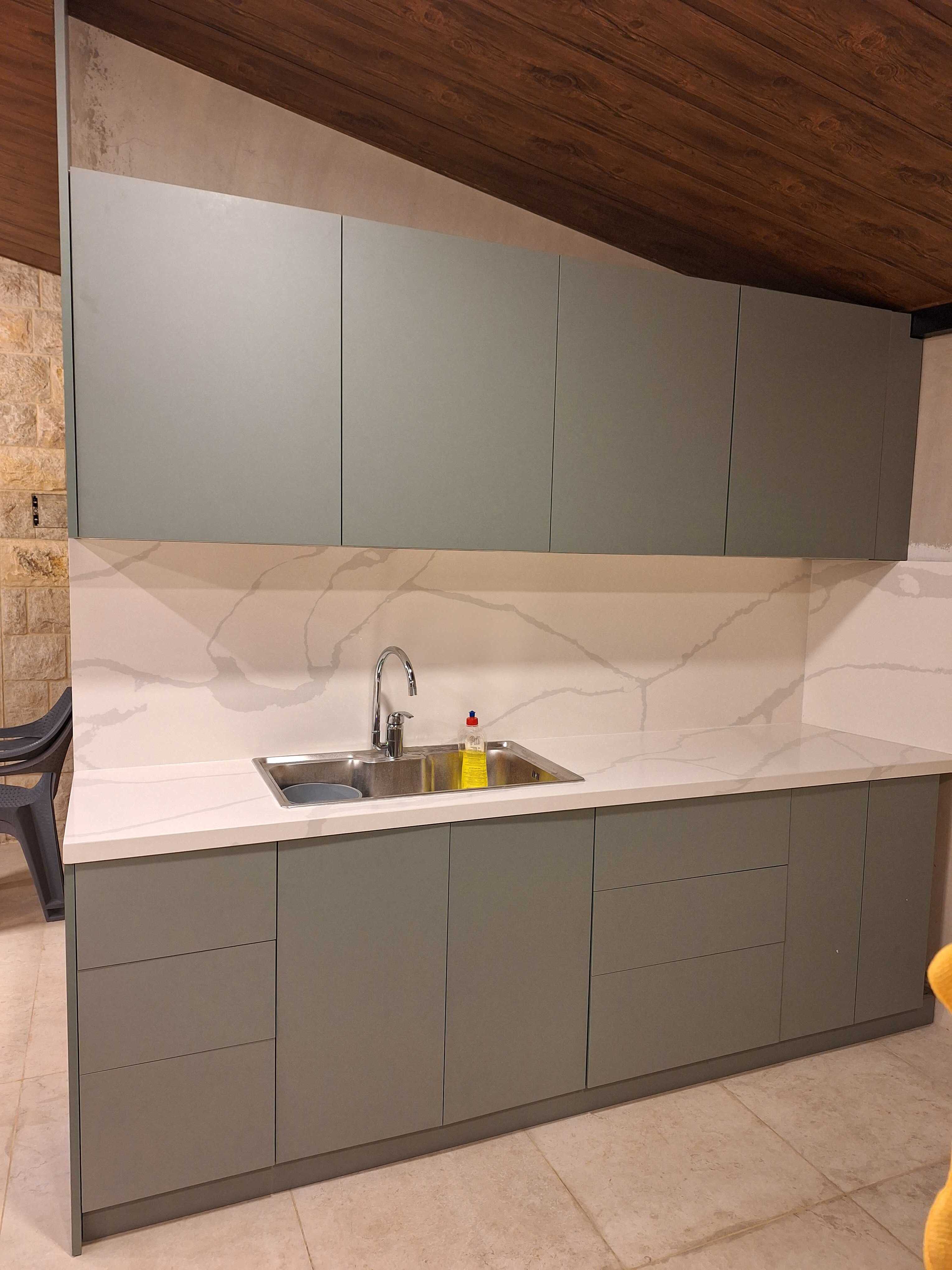 Front view of a Laurel Green kitchen with a marble-effect countertop and backsplash