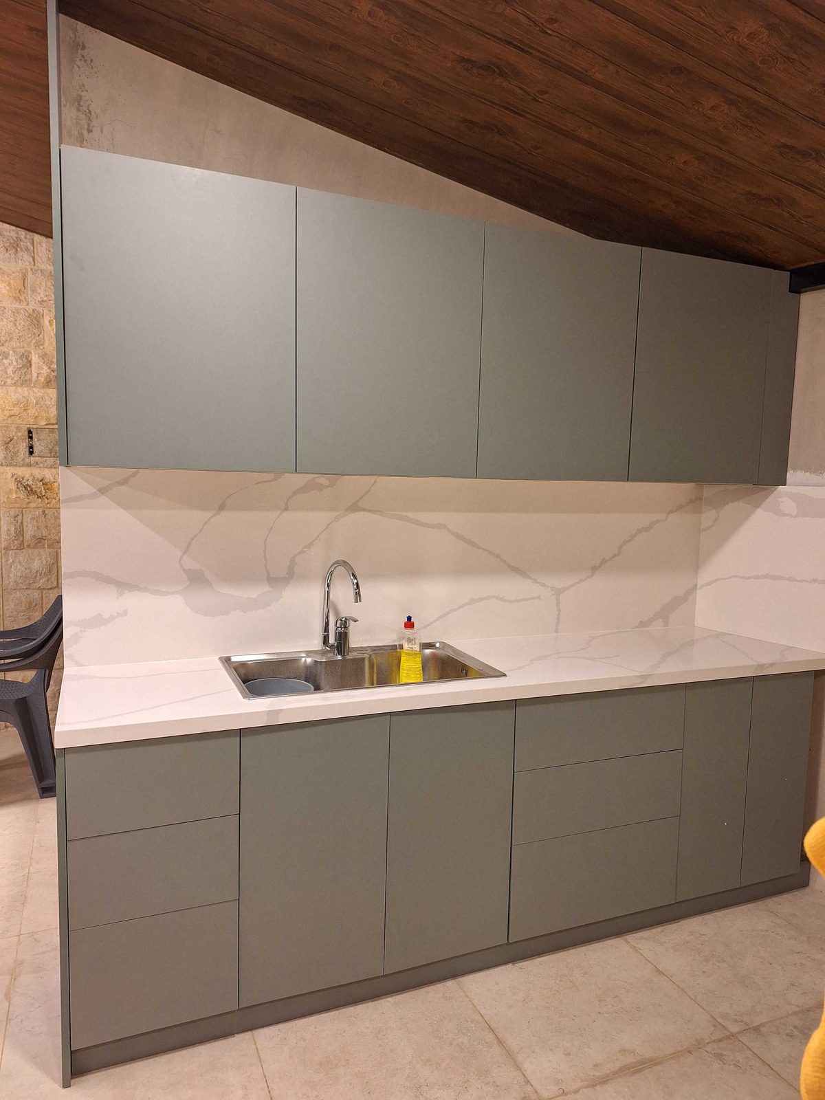 Front view of a Laurel Green kitchen with a marble-effect countertop and backsplash